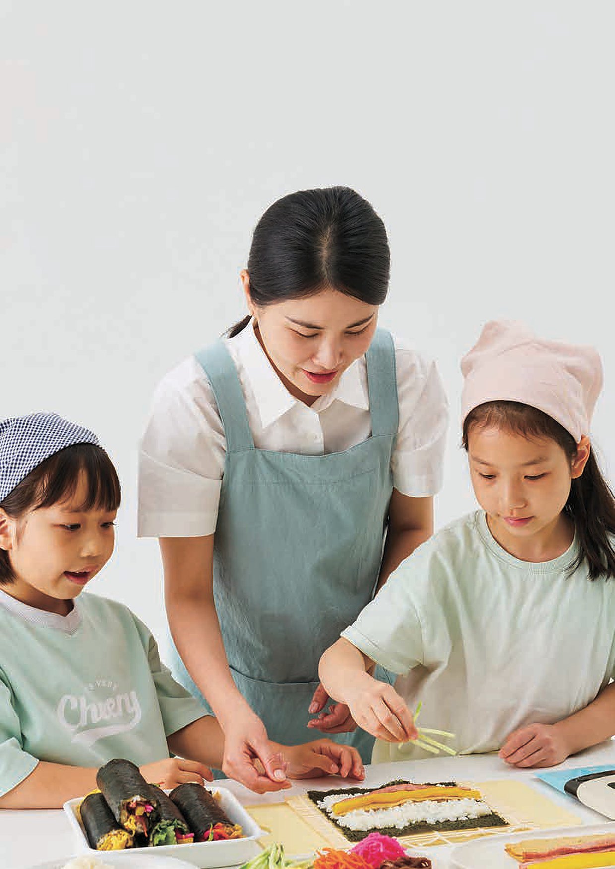 A mother and two children rolling gimbap together
